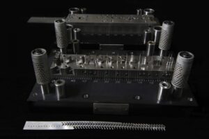 Progressive die metal stamping equipment on black background.