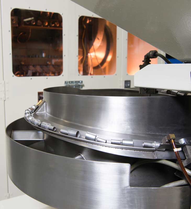 Vibratory bowl feeder sorting small metal components inside an automated manufacturing system.