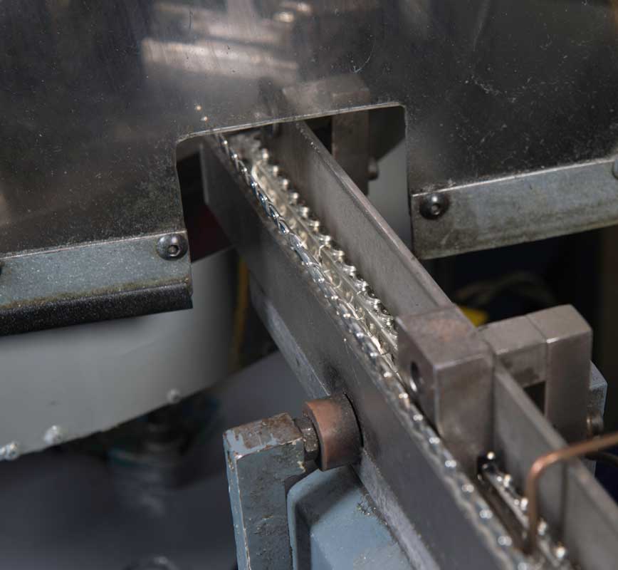 Metal slide forming machine feeding a strip of stamped parts through precision tooling.