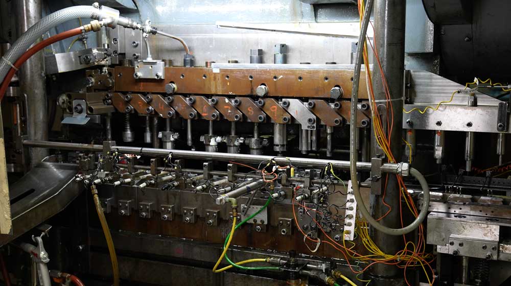 Multi-station metal stamping press with tooling, air lines, and wiring in an industrial manufacturing setup.